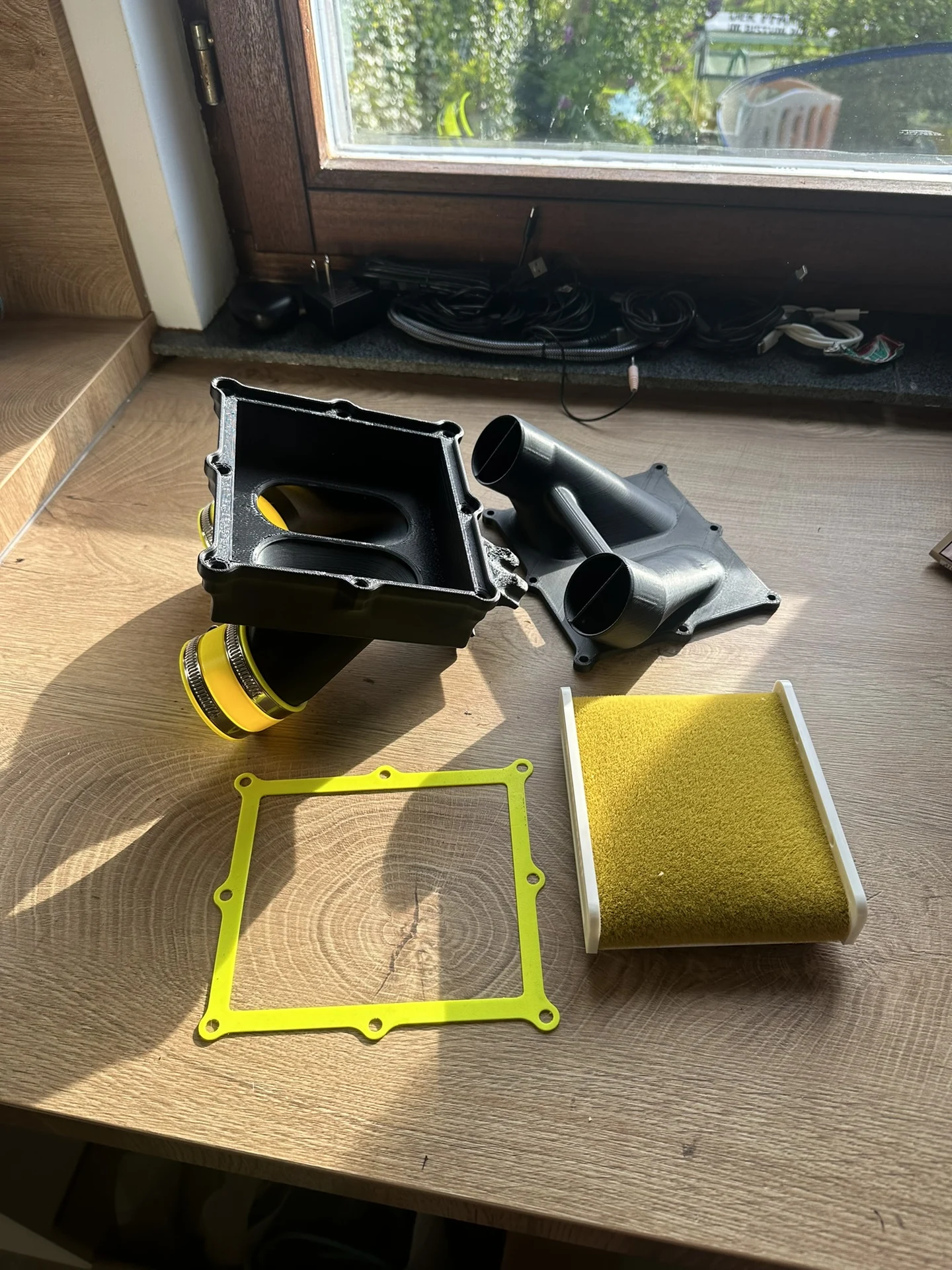 Luftfilterbox mit Gehäuseteilen, Dichtung und Filtereinsatz auf einem Tisch.