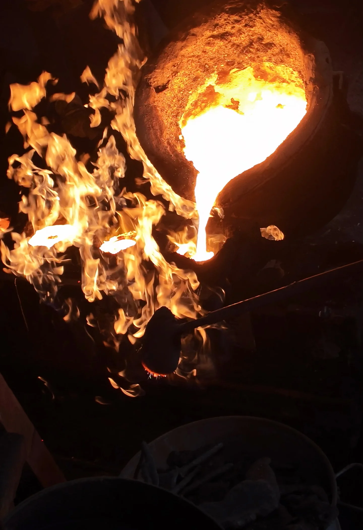 Einguss von flüssigem Metall aus einer Gießpfanne, mit Flammen.