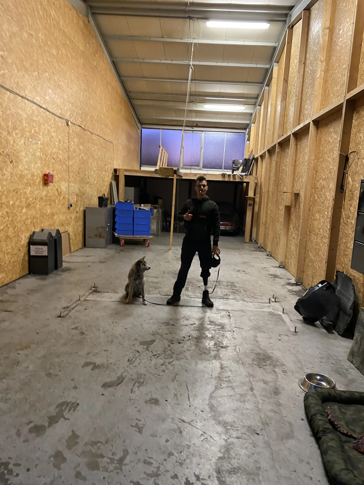 Leere Werkstatthalle in der Anfangszeit, eine Person mit Hund.