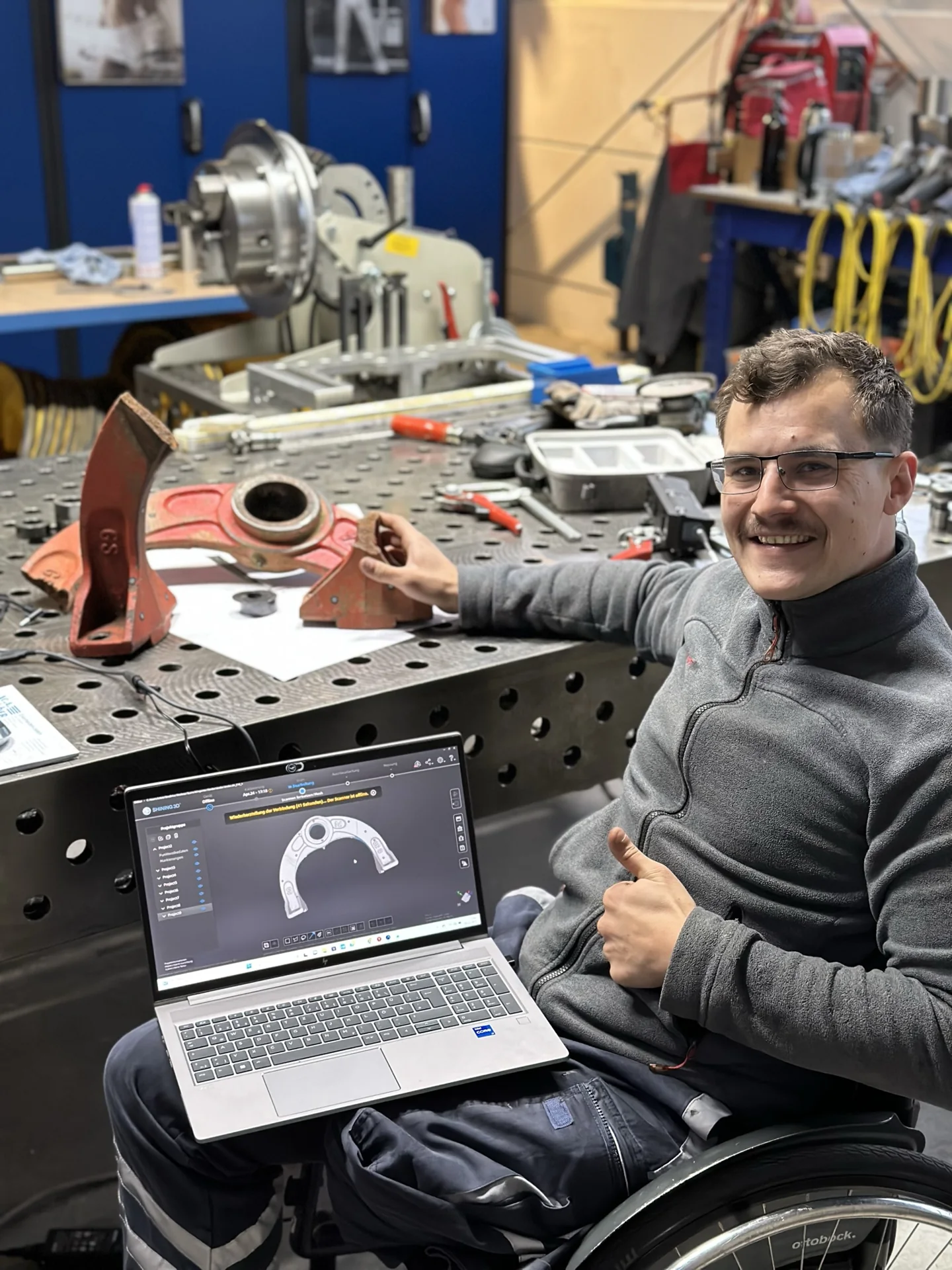 Lukas Heizmann mit der ursprünglichen Lagerbrücke am Arbeitstisch und dem digitalen Modell am Laptop.